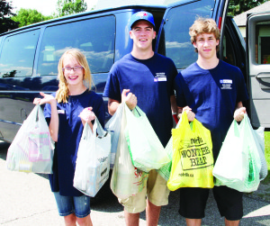 Camp participants took part in a food drive in Caledon village. Sydney Appleton, Michael Sheridan and Michael Andrews hold up some of the contributions they collected.