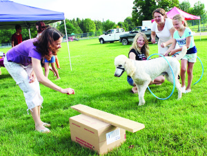 ‘INGLEWOOF' AT FARMERS' MARKET It was a time to celebrate the “dog days of summer” at Inglewood Farmers' Market recently. The activities included some fun items geared to canines. Karen Hutchinson of Eat Local Caledon and her daughter Katie Miller were helping Inglewood resident Michelle Jones and her daughter Lily Canning, 8, guide Prince through the hoops. Photo by Bill Rea