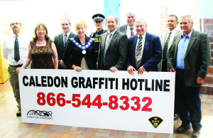 Mayor Marolyn Morrison recently officially unveiled the number of the Town's new Graffiti Hotline, accompanied by Councillors Nick deBoer, Patti Foley and Rob Mezzapelli, Caledon OPP Constable Clyde Vivian, Peel District School Board Trustee Stan Cameron, Councillors Richard Paterak and Doug Beffort, retired OPP sergeant Bob Patterson and Councillor Gord McClure. Photo by Bill Rea