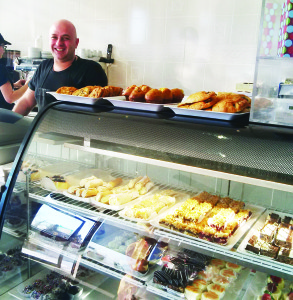 Gabe Giraldi stands behind the counter at his Country Bake Shoppe in Caledon East, in front of a fine array of pastries. Photo by Constance Scrafield