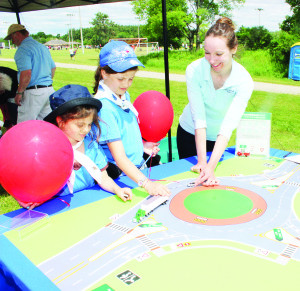 Katya Seckar, an education specialist with Peel Region Public Works was explaining how round abouts should be handled to people Violet Turner, 7, of Cedar Mills and her sister Jamie, 10.