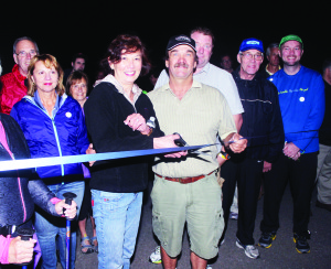 Daphne Parsons, financial controller of Brampton Flight Centre, and Caledon Councillor Nick deBoer cut this ribbon at one end of the runway at the facility last Thursday night, to start participants on their walk to the other end in the Light Up the Runway Walk, in support of Bethell Hospice. Photo by Bill Rea