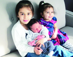 Munriya and Bahni Atwal hold their new baby brother Yuvraj.