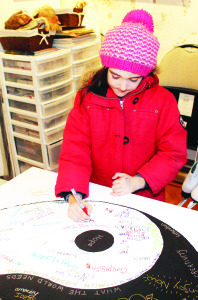 Mackenzie Arseneau, 7, of Shelburne was contributing to a collective word “mandala,” a circular design made up entirely of written words, inspired by Mill artist CJ Shelton.
