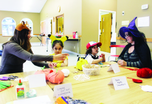 CHILDREN'S HARVEST FEST AT CHURCH There was lots of Halloween fun to be had Saturday at the All Hallow's Eve Children's Harvest Fest at St. John's Church on Highway 9. The fun included crafts of the season, and Sarah Houghton was assisting Veronica Geadah, 6, and her brother Sebastian, 4, with their creations, along with their mother Sandy. Photo by Bill Rea