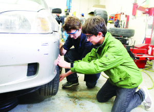 Grade 11 student Calvin Carew was showing Allan Drive Middle School student Ethan Mumford some of the things taught in auto shop.
