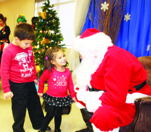GETTING TO MEET SANTA The Mayfield West Community hosted Santa Claus at the Margaret Dunn branch of Caledon Public Library Saturday, and there were lots of excited young people on hand to meet him, including Matteo Villacis, 5, and his sister Gabriella, 2, of SouthFields Village. Photo by Bill Rea