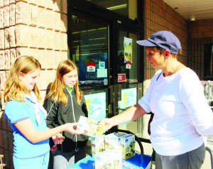 COOKIE SALES ARE BRISK It's the time of the year again when Girl Guides are out selling their cookies, and these two members of the 1st Caledon East Guides were busy serving customers last Saturday. Bernadette Langen and Jenna Early made a sale to Jay Laird. Photo by Bill Rea