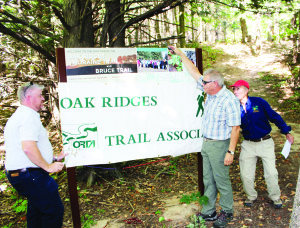 Brian Millage, regional director of the Oak Ridges Trail Association (ORTA) watched as Dave Robitallie, director of corporate citizenship and corporate affairs for IBM Canada Ltd., and Kevin Lowe, president of ORTA, unveiled the kiosk. Photo by Bill Rea
