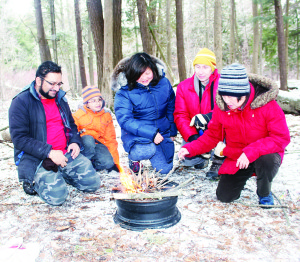 LEARNING WILDERNESS SKILLS Members of the Community Engagement Team of Toronto and Region Conservation Authority were running a course at Albion Hills Conservation Area Saturday, teaching people wilderness skills. Participants had to demonstrate their ability to start a fire, build temporary shelters, etc. Saad Malik of Mississauga and his son Danial Saad, 8, were admiring the fire thy created with Eleanor Sim, Doug Howarth and Diana Howarth of Toronto Photo by Bill Rea